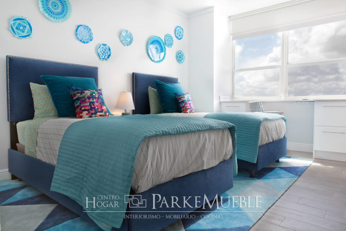 dormitorio con camas gemelas decorado con cojines y manta